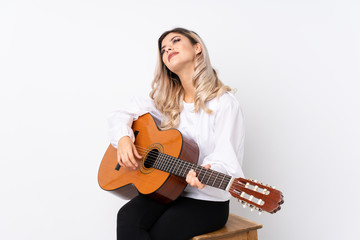Teenager girl with guitar over isolated white background looking up while smiling