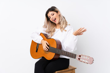 Teenager girl with guitar over isolated white background with shocked facial expression