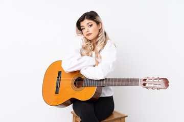 Teenager girl with guitar over isolated white background making doubts gesture while lifting the shoulders