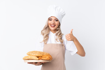 Teenager girl in chef uniform. Female baker holding a table with several breads over isolated white background giving a thumbs up gesture