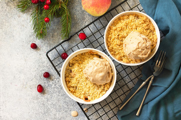 Homemade winter dessert. An apple crumbles with cranberries served with a ball of caramel ice cream on a stone or slate countertop background. Top view of a flat lay.