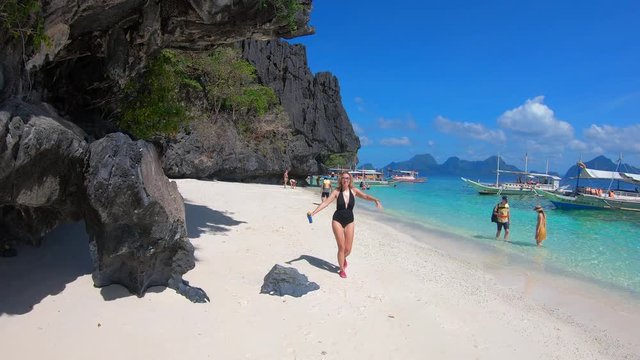Happy young woman in bikini walking on the tropical beach in El Nido, Palawan, Philippines