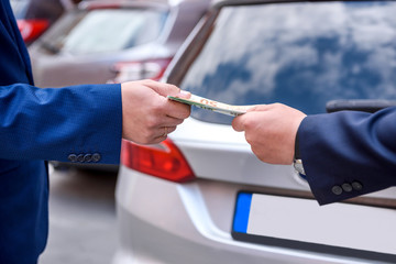 Male hands with euro banknotes against car