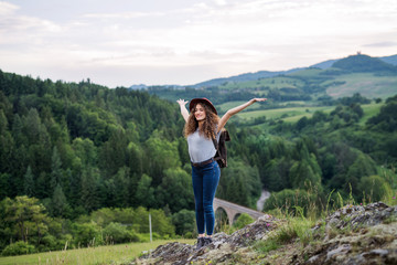 Young tourist woman hiker with backpack standing in nature, resting.