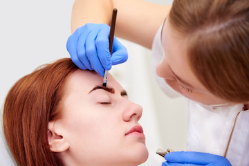 Young woman on eyebrow correction in cosmetology clinic.