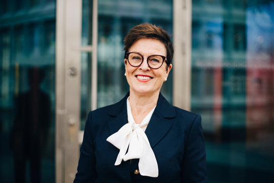 Portrait of confident smiling senior businesswoman against office