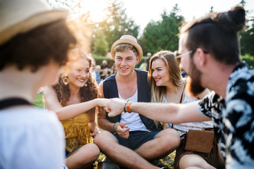 Group of young friends sitting on ground at summer festival.