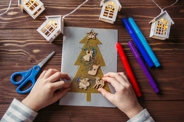 the child makes a New Year card for the winter holidays. DIY crafts and crafts for Christmas do-it-yourself concept