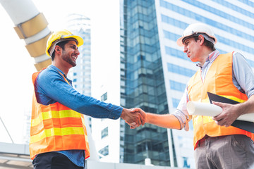 Engineer in Yellow helmet and best greeting with warm handshake manager visiting site. Modern...