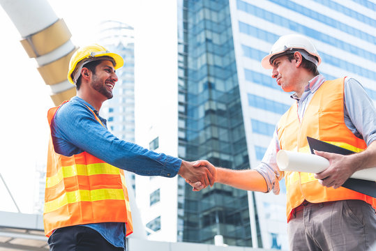 Engineer in Yellow helmet and best greeting with warm handshake manager visiting site. Modern construction and engineering concept. Safety of work in production and construction work place.