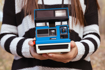 Detalle de manos de mujer sujetando cámara de fotos instantánea de color azul