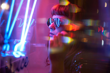 Fototapeta na wymiar girl with sunglasses and fringe looking at neon lights