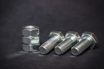 Metal bolts and nuts on black background are used in construction