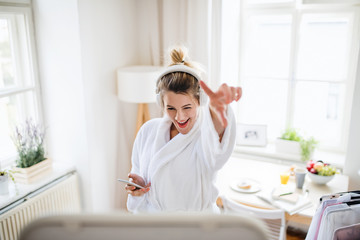 Young woman with headphones indoors at home in the morning.
