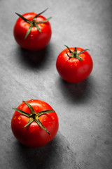 Three tomato with drops. Full depth of field. Fresh red ripe tomatoes for use as cooking ingredients in the foreground on dark background. Harvesting tomatoes. Top view