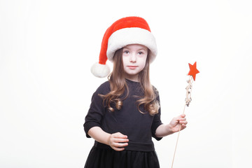Happy girl in santa hat with star in her hand. Funny young child waiting for christmas, new year...