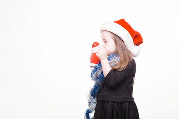 Happy girl in santa hat with christmas toys on white background. Funny young child waiting for christmas, new year and presents. holiday, sale concept with place for text