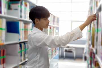 In the library, asian female student search book between the shelves