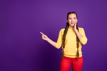 Fototapeta premium Photo of pretty lady long braids indicating finger empty space advising cool low shopping prices wear casual yellow pullover red trousers isolated purple color background
