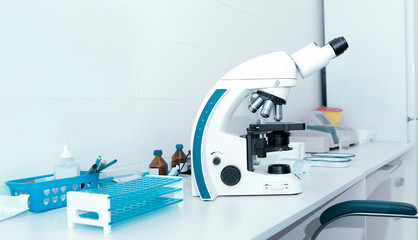 Close up of microscope on table with test tubes and other equipment