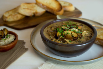 Food photography of a creamy mixed mushroom soup with herbs and toasted bread on a white surface