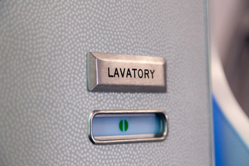 Vacant green sign, vacant symbol on an airplane lavatory door. Raised, brushed metal lavatory sign, recessed plastic vacant sign. Toilet room, wc, closet on airplane board