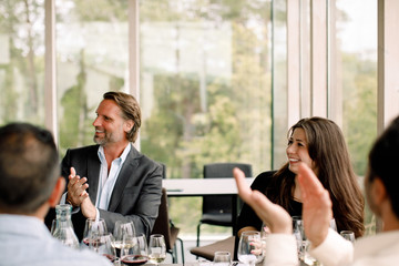 Smiling business professionals applauding during kick off meeting at convention center