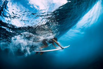 Surfer make duck dive underwater. Surfgirl dive under wave