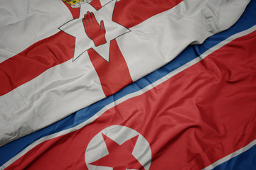waving colorful flag of north korea and national flag of northern ireland.