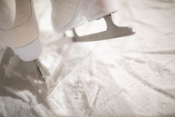 women's white figure skates on the rink.