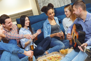 Group of friends having party indoors fun together guy playing guitar - Powered by Adobe