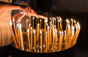 Woman lights candles in the Church of the Holy Sepulchre Jerusalem