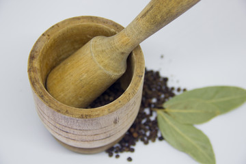 wooden mortar, black pepper, bay leaf on a white background