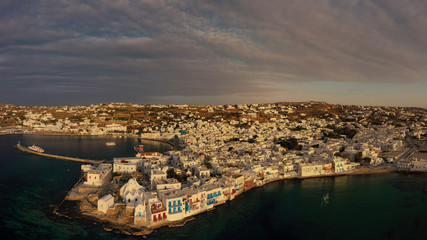 Aerial drone panoramic photo of picturesque old port in main village of Mykonos island at sunset and iconic church of Paraportiani with beautiful colours, Cyclades, Greece
