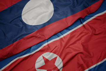 waving colorful flag of north korea and national flag of laos.