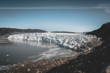 Greenland, Eqip Sermia, Eqi Glacier in Greenland Disko Bay. Boat trip in the morning over the arctic sea,Baffin Bay, calving glacier. Ice breaking of on a blue sky wth clouds.
