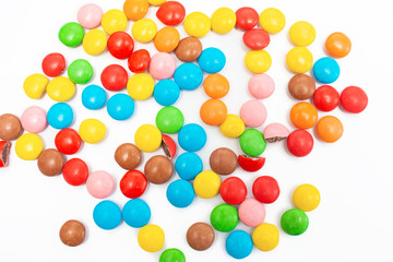Many multi-colored small round candy pills are scattered on the table close-up
