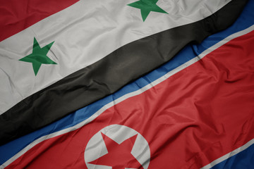 waving colorful flag of north korea and national flag of syria.