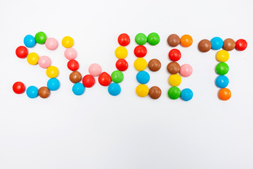 The inscription Sweet written in round small multi-colored sweets dragees on a white background