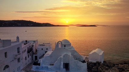 Fototapeta na wymiar Aerial drone panoramic view of landmark church of Paraportiani overlooking the Aegean sea in main village of Mykonos island at sunset with beautiful colours, Cyclades, Greece