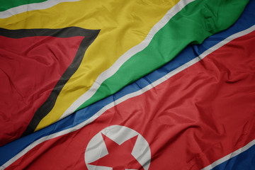 waving colorful flag of north korea and national flag of guyana.
