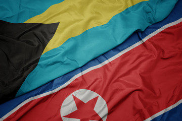 waving colorful flag of north korea and national flag of bahamas.