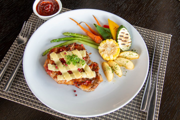  pork steak cheese on top in white plate