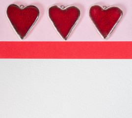 Red ceramic Valentines hearts on a pink and white paper background