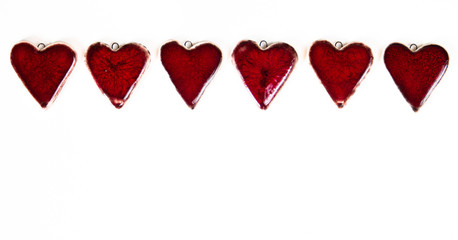 Red ceramic Valentines hearts on a white paper background