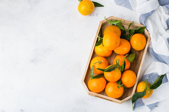 Fresh orange mandarins, tangerines with green leaves on a table © aamulya