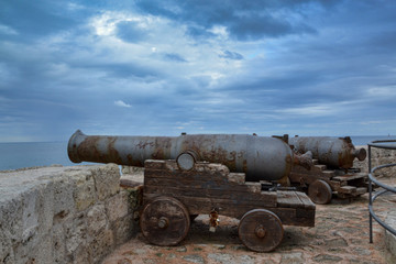 Fototapeta na wymiar Cannoni medievali al porto sul mare in Italia
