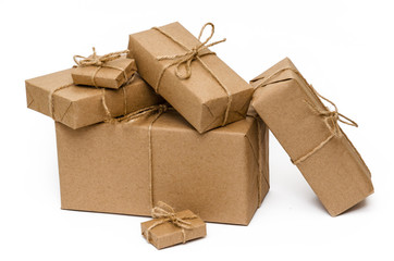 Pile of stacked boxes wrapped with brown kraft paper and tied with twine on a white background. Close-up. Delivery, moving, package and gifts concept