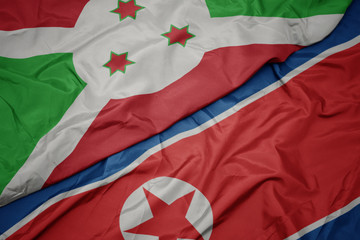 waving colorful flag of north korea and national flag of burundi .