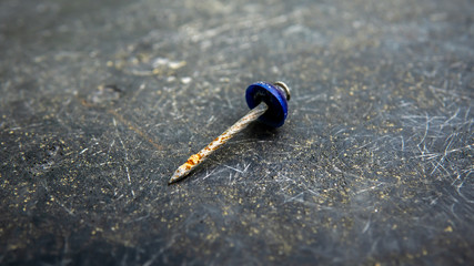 Close up view of rusty dull nail on the black scratches surface background.